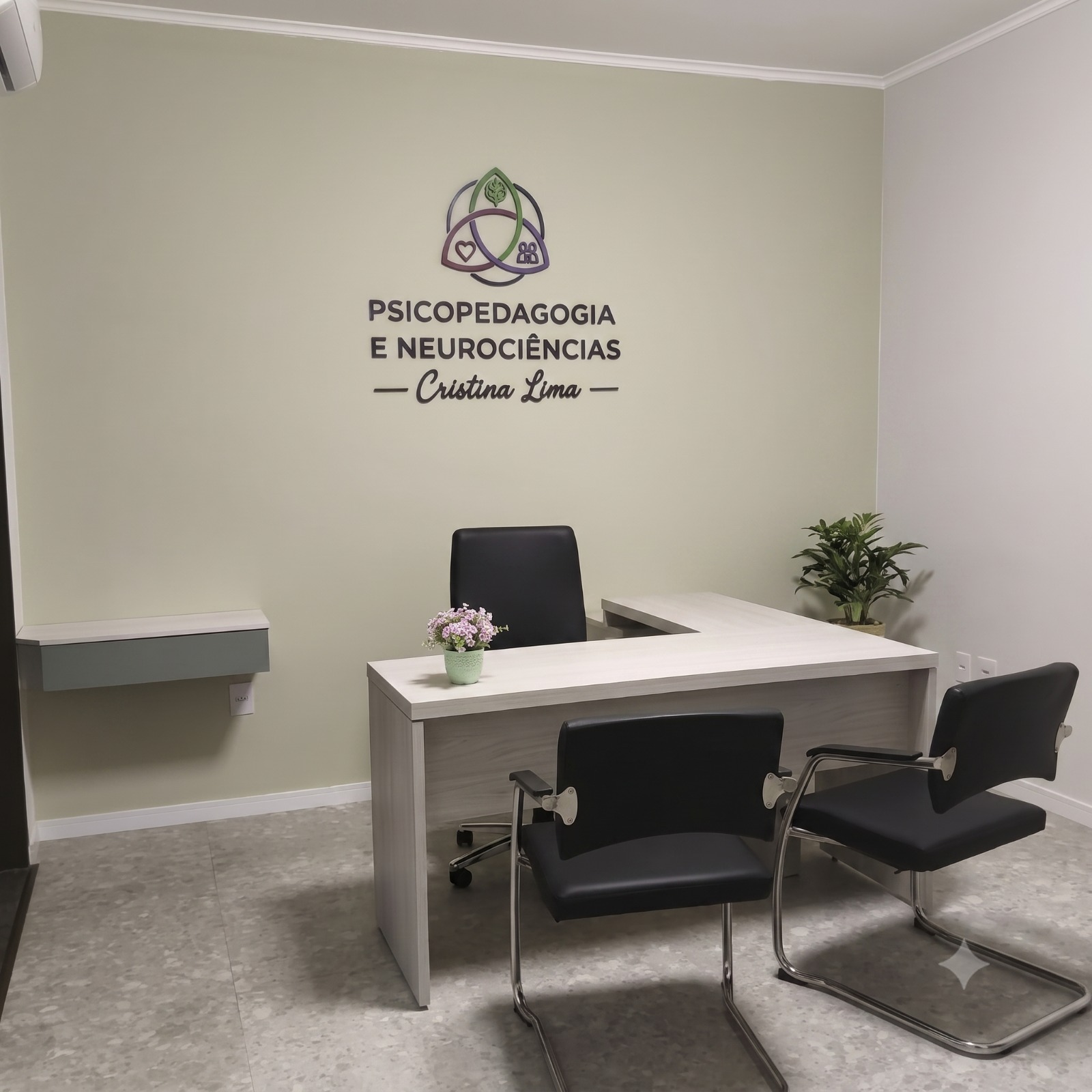 Consultório de Cristina Lima, com mesa de atendimento e identidade visual na parede